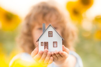 House in hand against spring green background. Real estate concept